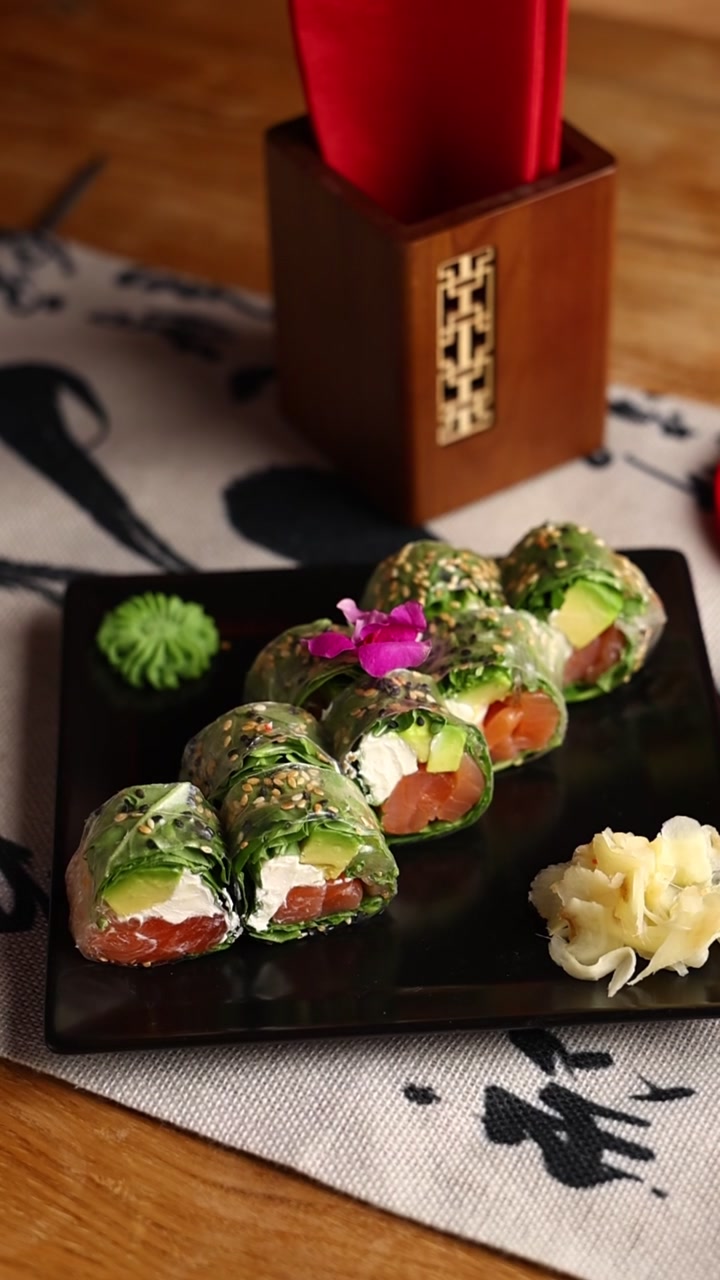 Involtini freschi di carta di riso con salmone e avocado su un piatto nero