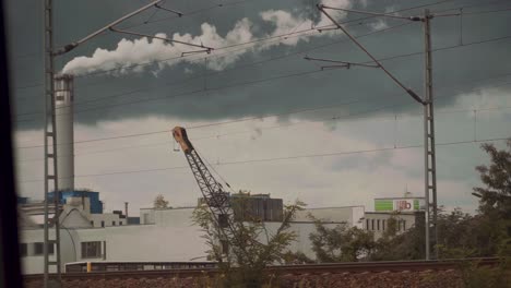 Smoke-rising-from-the-chimney-of-a-factory-as-seen-through-a-window,-pollution-and-climate-change