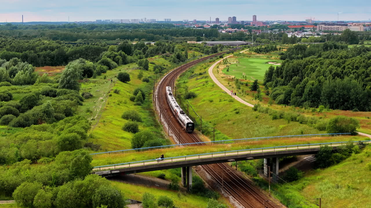 Aerial drone view of a train moving on the rails towards a city