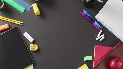 video of school supplies and notebooks, paper clips, pens over black background