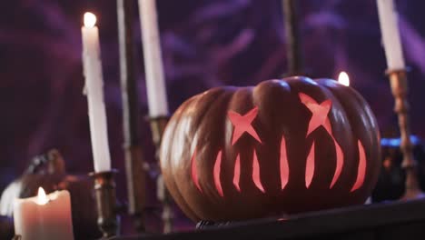 Video-of-halloween-carved-pumpkin,-candles-and-smoke-with-copy-space-on-purple-background