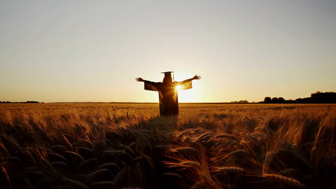En person i silhuett står med utstrakte armer på en hvetemark ved solnedgang, noe som skaper en fredelig og rolig stemning. Øyehøyde-perspektivet og de naturlige omgivelsene gjør denne scenen ideell
