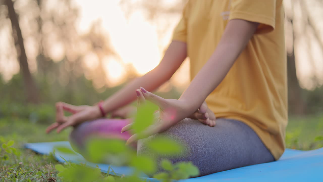 Close up shot of a woman practicing apana mudra in nature during golden hour