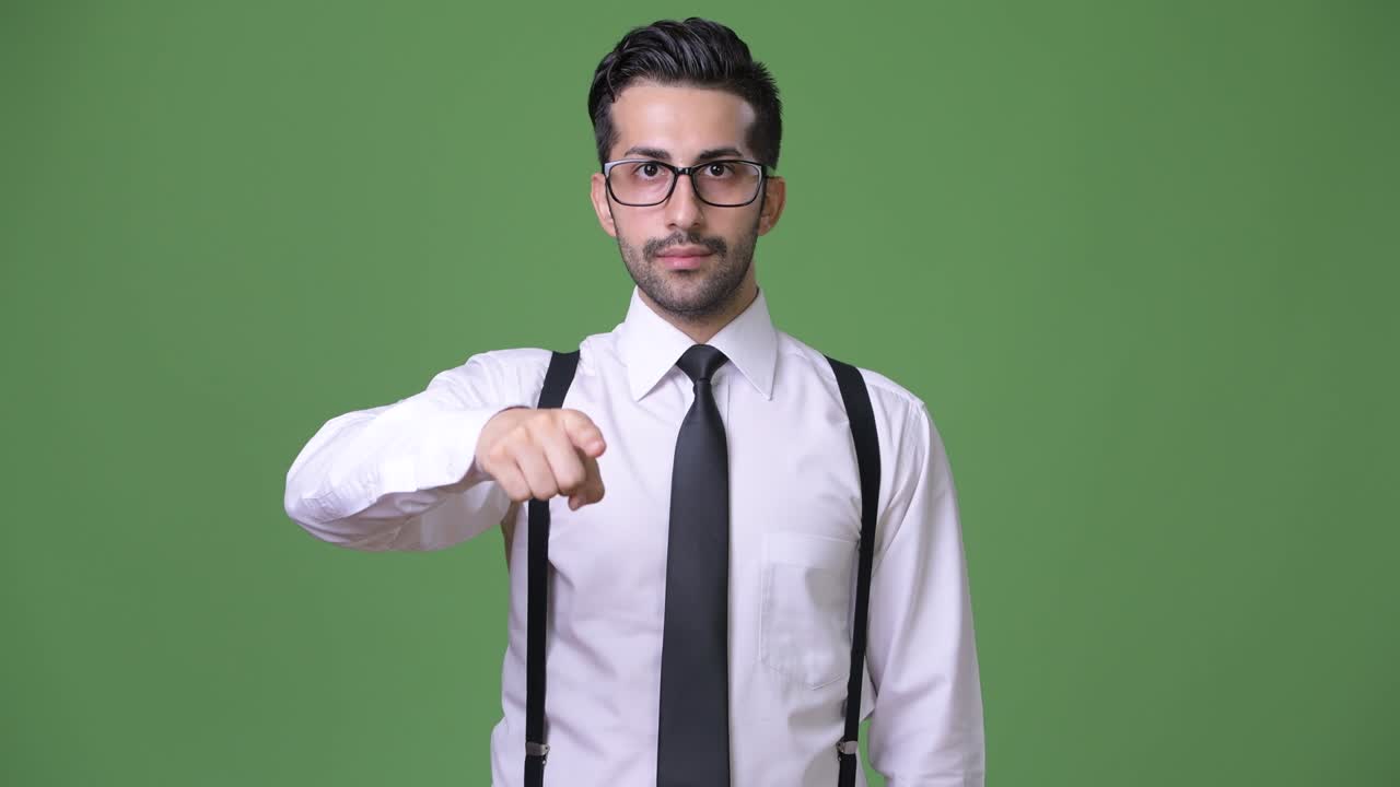 joven empresario persa barbudo y guapo contra un fondo verde