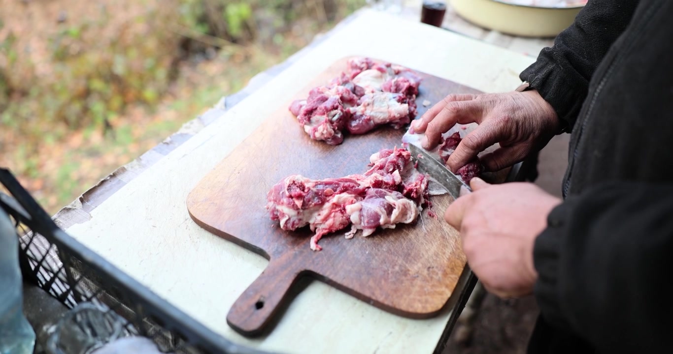 Elaborando platos tradicionales con carne fresca en un entorno rústico al aire libre