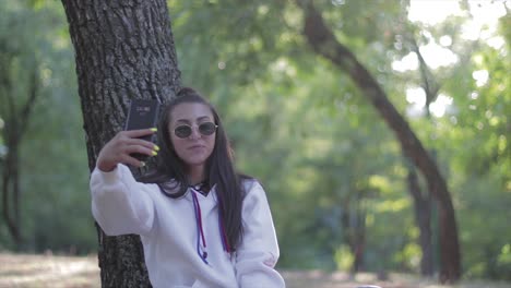 Junges-Schönes-Mädchen,-Das-Ein-Selfie-foto-Mit-Ihrem-Telefon-In-Einem-Park-Macht