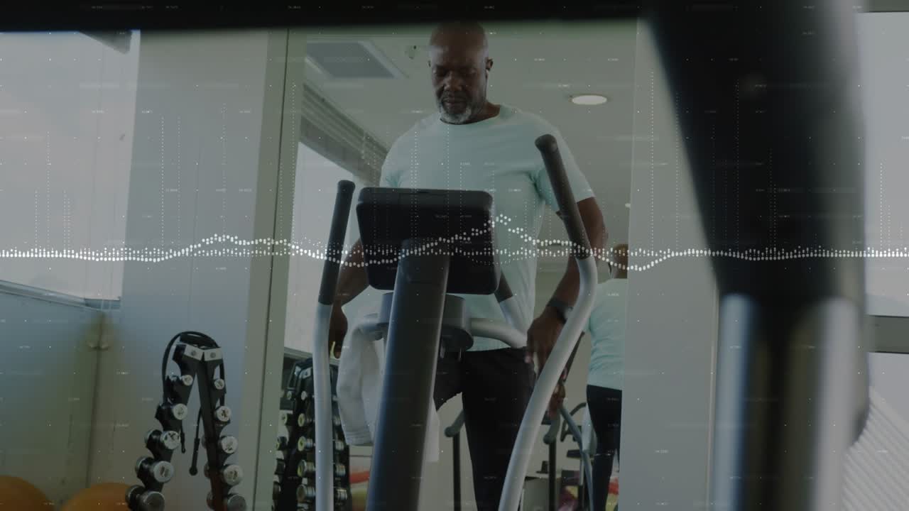 Mature man wiping face then placing towel on console, checking display and starting fitness workout