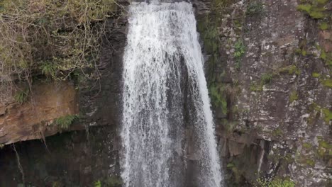 An-slow-motion-aerial-view-of-Melinclourt-Waterfall-on-an-overcast-day,-Neath-Port-Talbot,-South-Wales