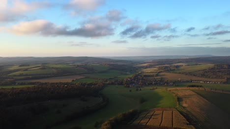 Aerial-shot-flying-backwards-over-fields-and-farmland-in-Sussex,-England