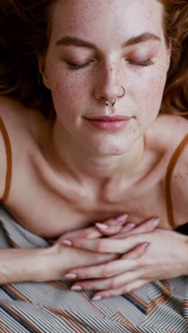 peaceful portrait of a woman with freckles and a nose piercing