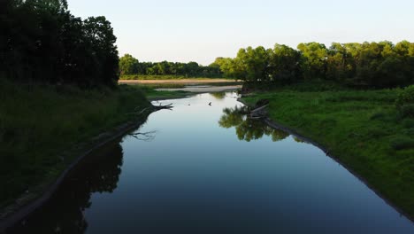 Drone-flying-through-creek-mouth-and-showing-horseshoe-bend-in-the-river-with-a-house-right-in-the-middle