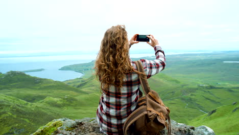 woman taking photo of scenic landscape from mountaintop