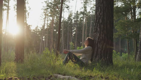 woman sitting in a forest at sunset