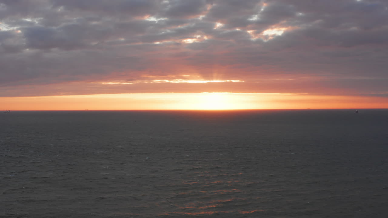 Il faro di Westkapelle durante un tramonto arancione vivido, con molto vento