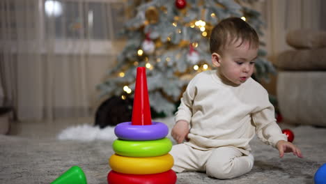 baby playing with stacking rings near christmas tree