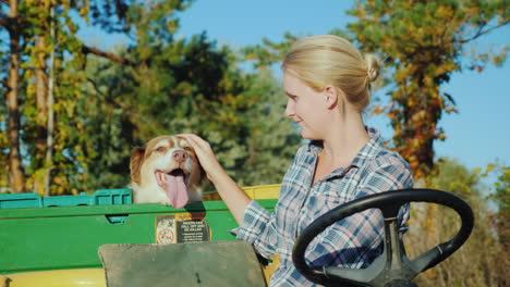 una agricultora en un pequeño tractor recorre su granja junto a su perro