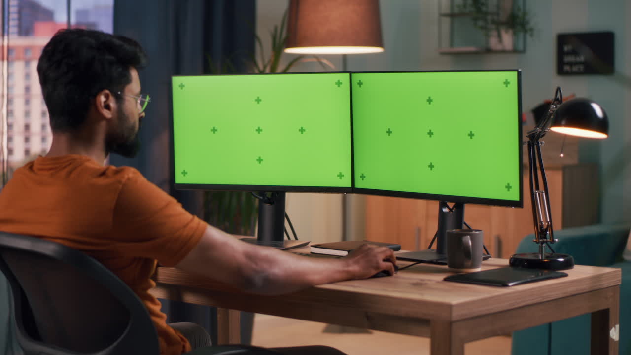 Person working from home on a dual monitor set up with green screen displays