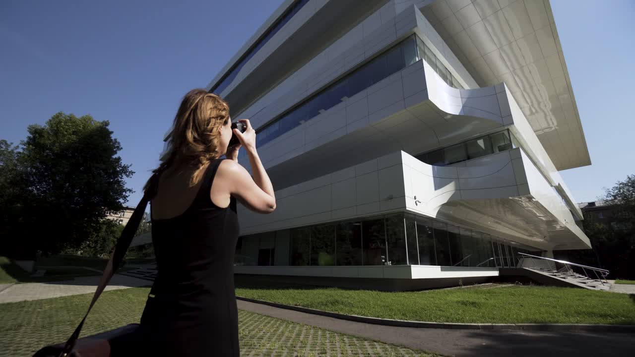 mujer tomando una foto de un edificio moderno
