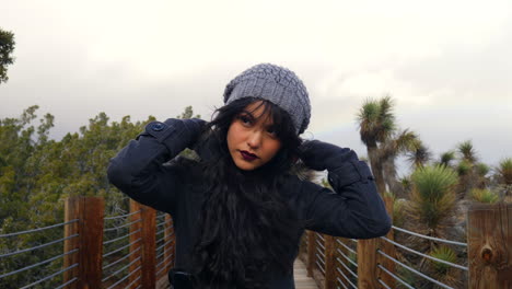 Attractive-girl-in-a-rain-storm-putting-her-hood-up-to-stay-warm-with-a-colorful-rainbow-in-the-distance-during-bad-weather