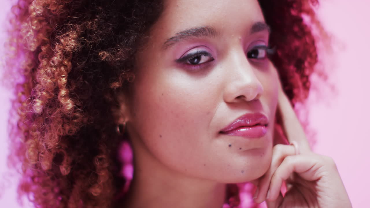 mujer biracial con cabello oscuro en luz rosa, cámara lenta