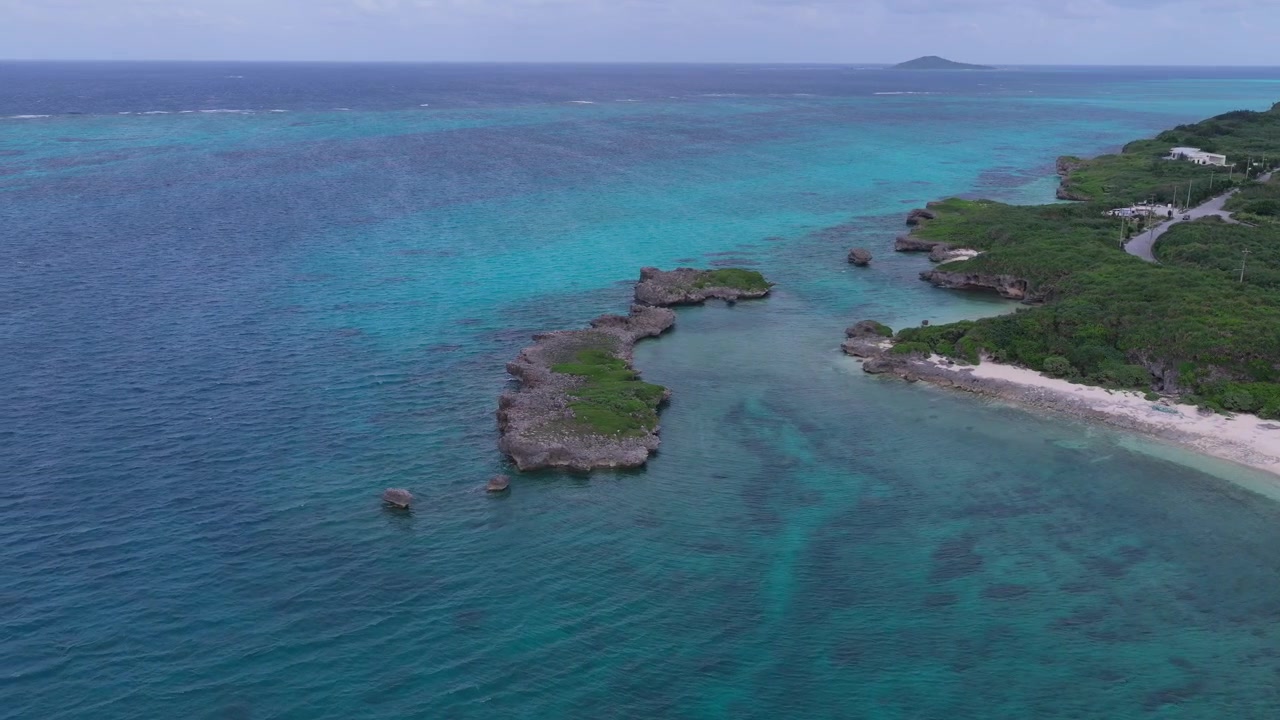 Riprese aeree orizzontali con movimento laterale a sinistra lungo la costa rocciosa e le acque turchesi di Kaginmi Beach, Isola di Ikema, Okinawa, Giappone