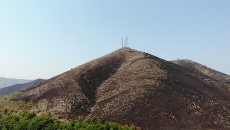 peak of mountain covered by black ash from burned grass and trees after a fire