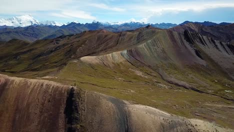 Aerial,-tracking,-drone-shot-around-a-hiker-trekking-on-the-Palcoyo-rainbow-mountain,-in-Red-Valley,-sunny-day,-in-Andes,-Peru,-South-America