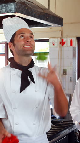 el jefe de cocina haciendo malabarismos con las verduras y los colegas mirando