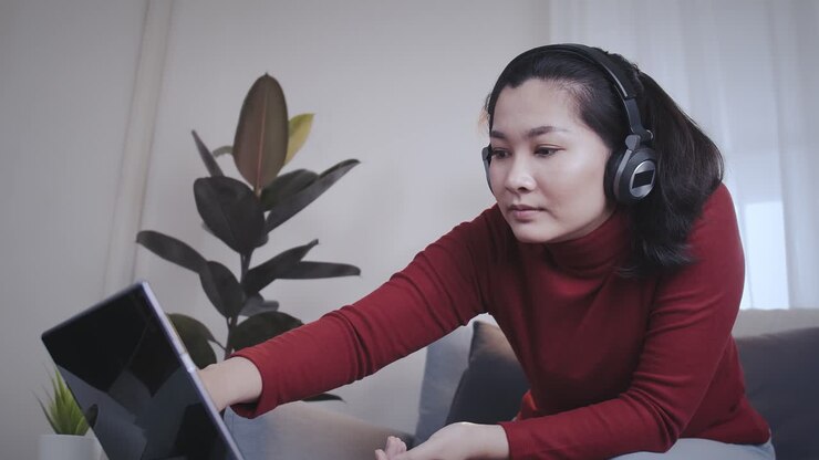 Freelance woman redshirt using tablet with headphone for meeting online at home
