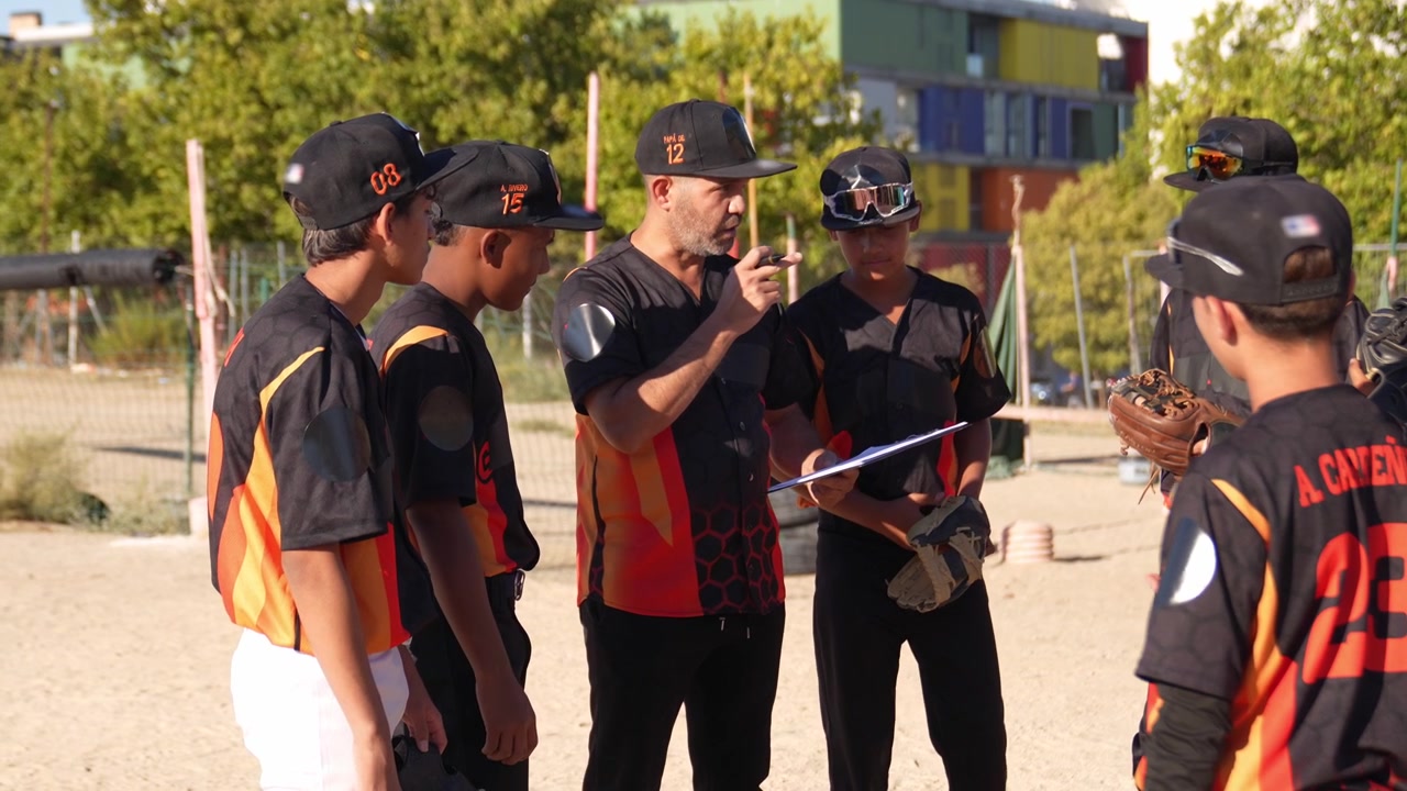Allenatore di baseball che dà istruzioni a una squadra giovanile sul campo.