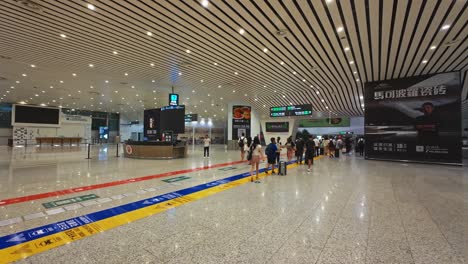 travelers walking through a modern airport terminal with luggage and bright signs above