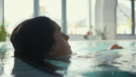 Eine-Junge-Frau-Ist-In-Einem-Pool-Zu-Sehen,-Wo-Sie-Sich-Nach-Dem-Schwimmen-Entspannt