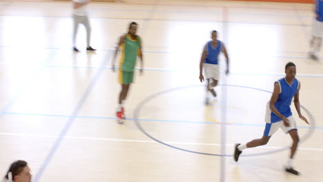 multiracial male basketball players with coach walking and observing game in gym