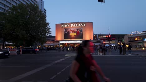 people gather outside the iconic zoo palast cinema in berlin during the evening, highlighting the lively atmosphere in the city.