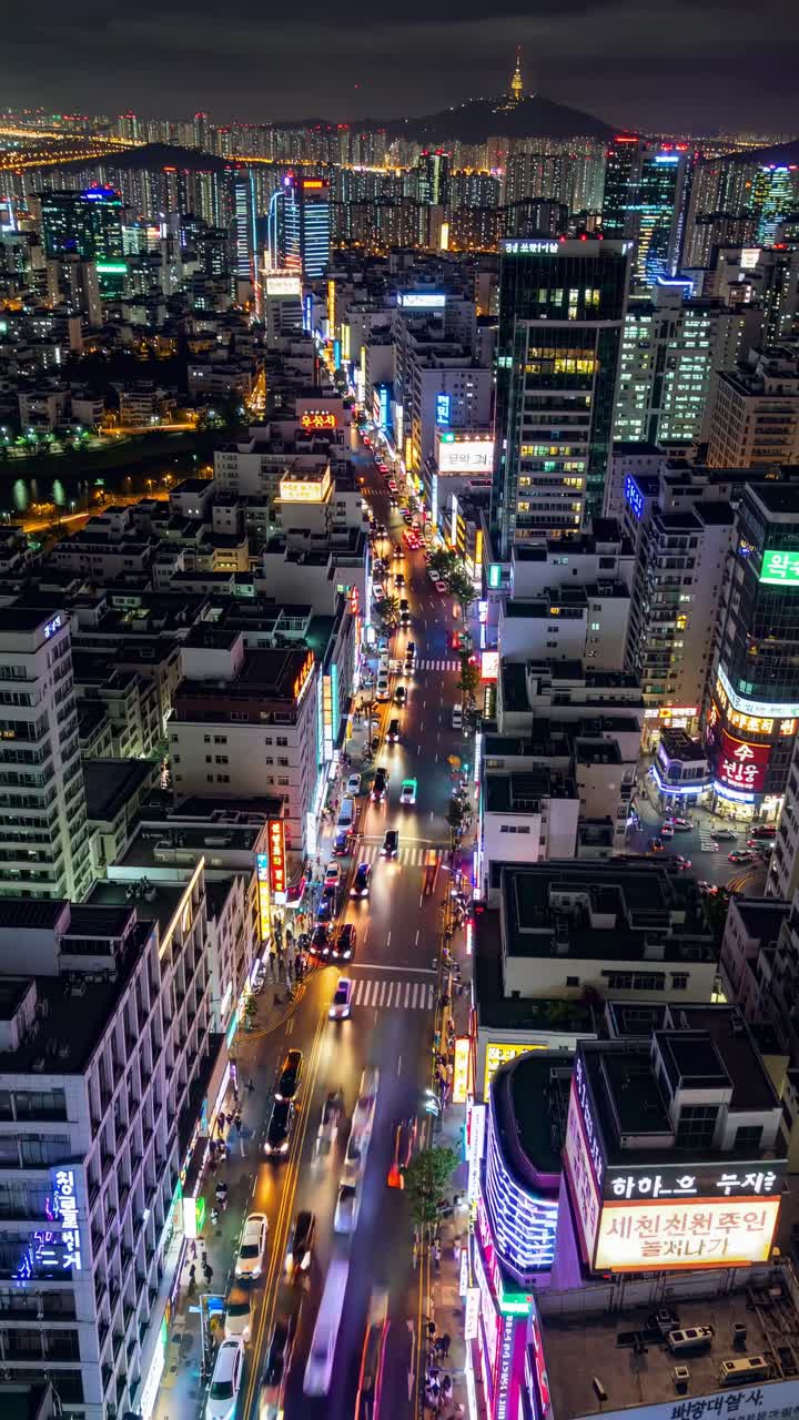Aerial view of a vibrant cityscape at night, showcasing bustling streets and illuminated