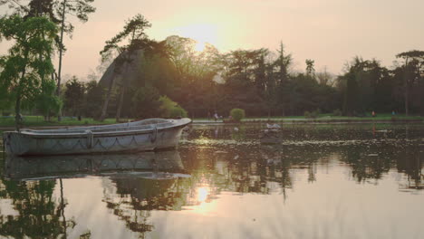 A-static-shot-of-an-abandoned-boat-in-the-middle-of-the-lake-of-the-Vincennes-Woods-Parc-at-sunset-in-Paris,-France