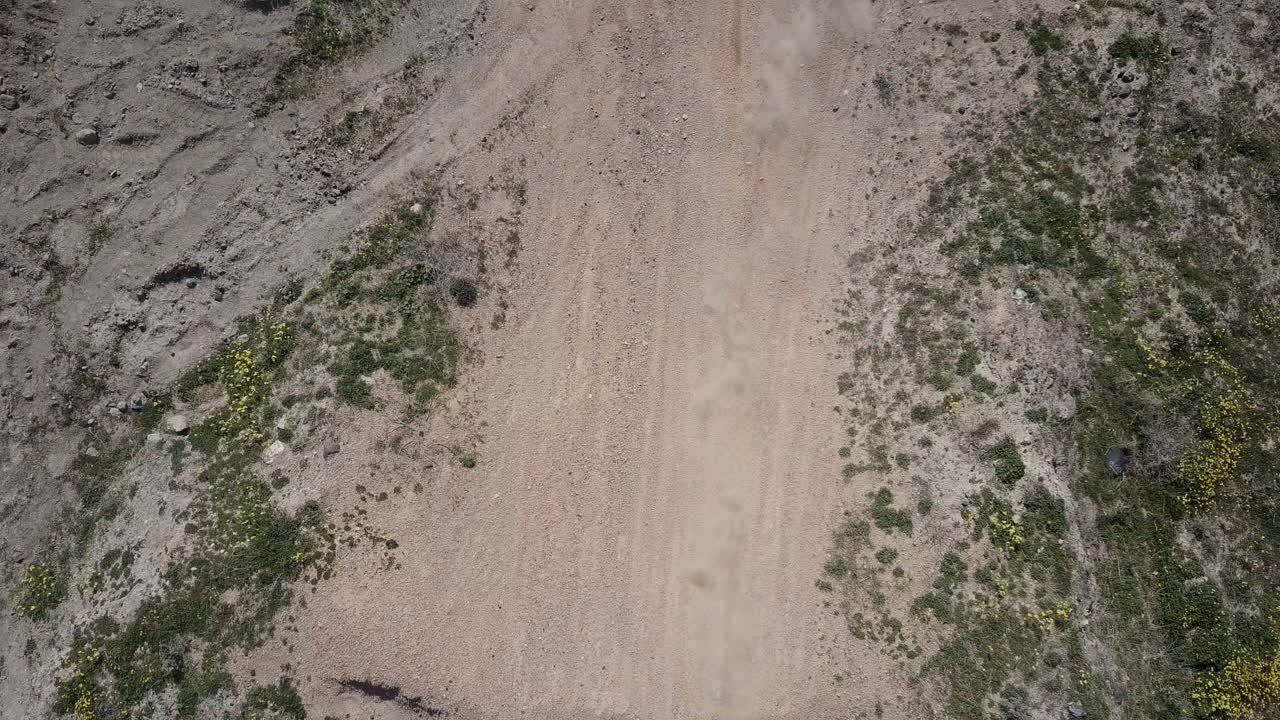 toma aérea de dos motociclistas pasando por debajo de la cámara, panoramizando hacia abajo