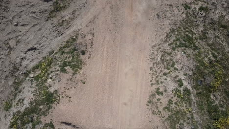toma aérea de dos motociclistas pasando por debajo de la cámara, panoramizando hacia abajo