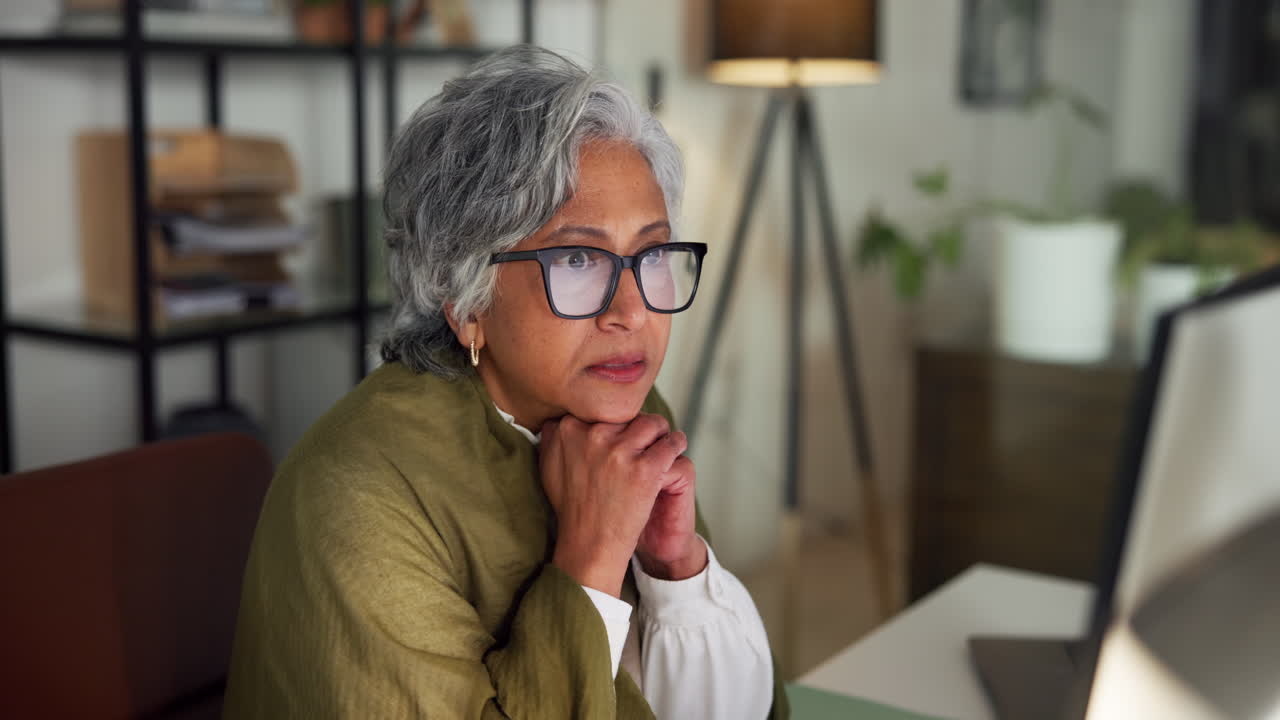 Mature Woman with Glasses Focused on Laptop Screen