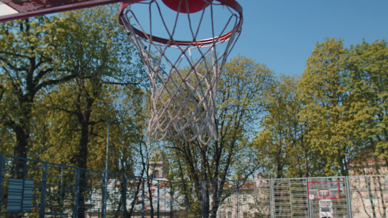 Athletic man in sportswear playing basketball game successfully throws ball into the basket ring