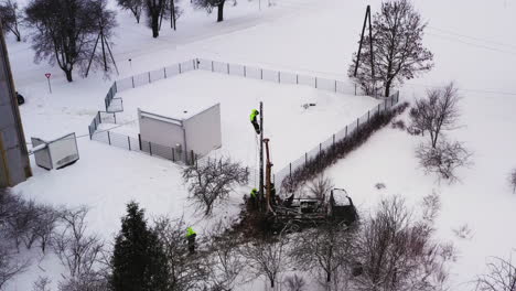 liniero trabajando en un poste eléctrico con cables de fijación de equipos de seguridad, vista aérea en invierno