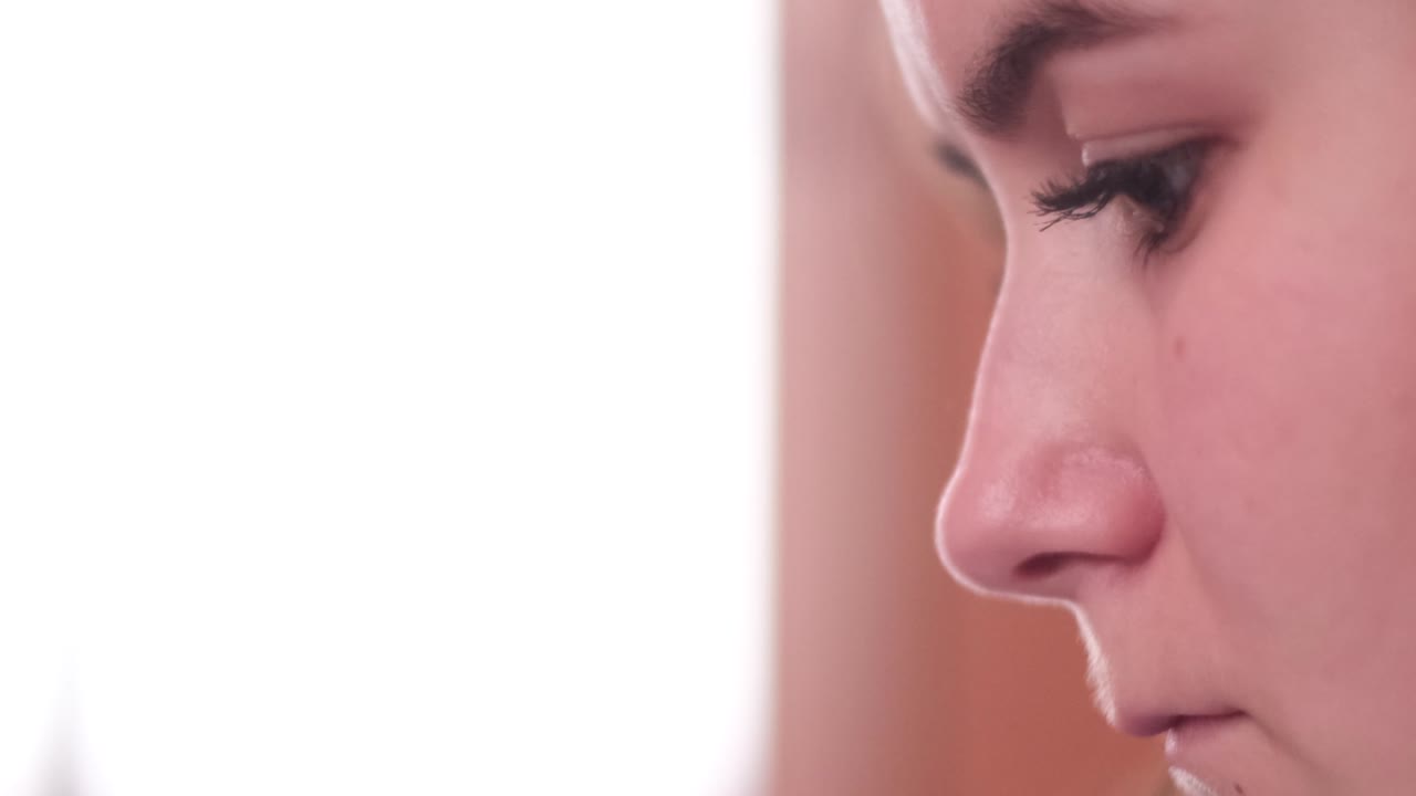 Close up of the face of a girl looking at a smartphone, her eyes tired, blinking eyes