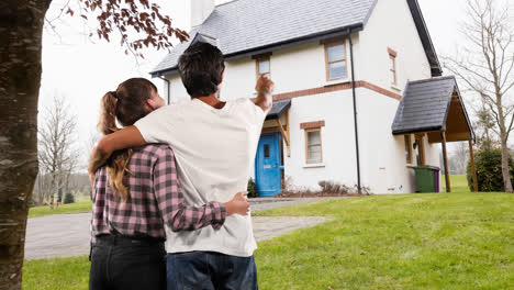 Caucasian-couple-looking-happy-in-front-of-their-house-