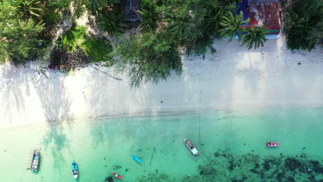 Hermosa-Playa-De-Arena-Blanca-Con-Palmeras-Bañadas-Por-Una-Laguna-Turquesa,-Barcos-Anclados-En-La-Costa-De-Una-Isla-Tropical-En-Tailandia