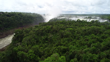 drone rises above central america forest to misty iguazu falls in deep tropical jungle