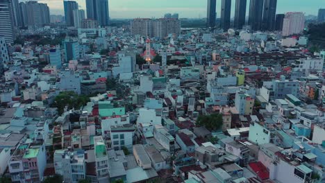 Early-morning-drone-fly-in-over-modern-urban-rooftops-away-from-illuminated-French-colonial-Catholic-Church-and-massive-high-rise-buildings