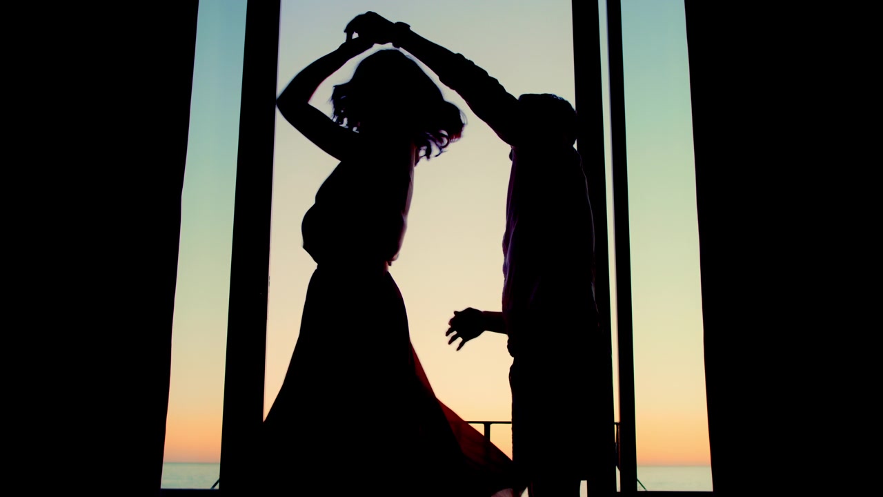 Silhouette di una Coppia Romantica che Balla su un Balcone al Tramonto