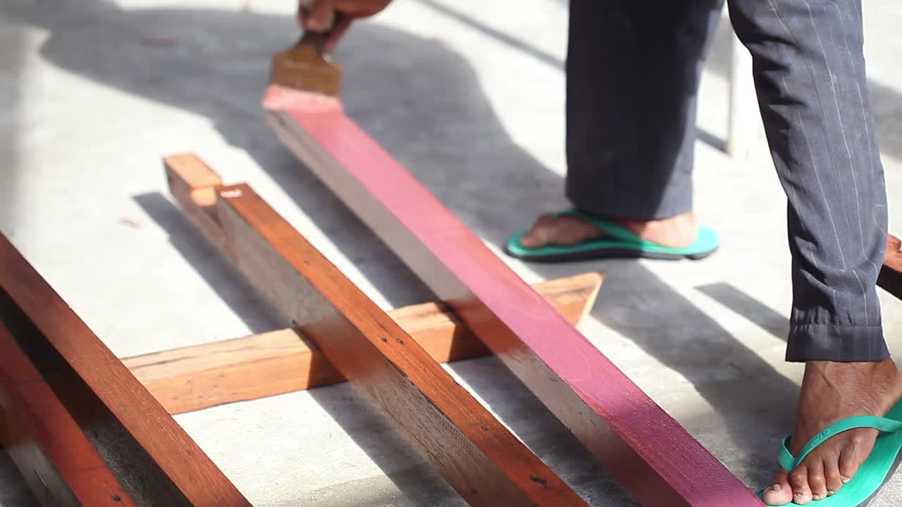 A carpenter is painting wood for building