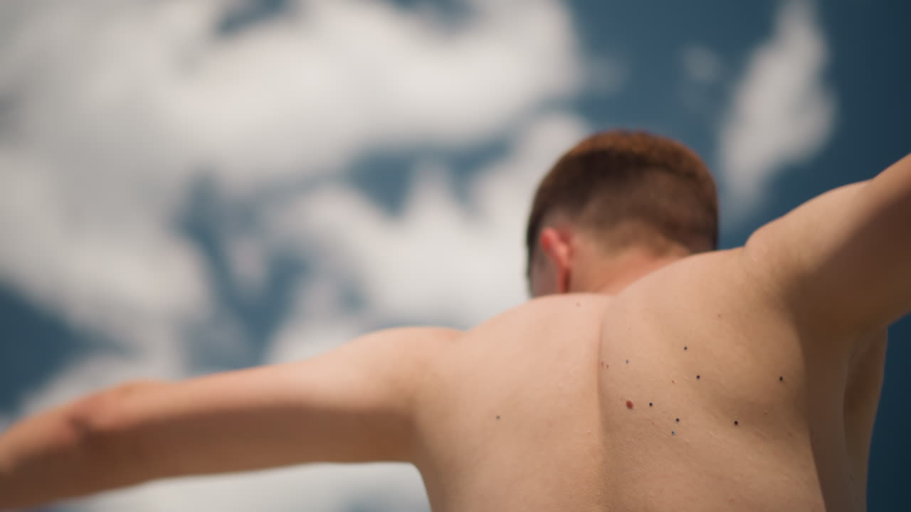 빛나는 하늘 아래에서 행복을 표현하는 개인, 밝은 햇빛 아래에서 팔을 벌려 자유를 만끽하는 사람, 화창한 야외에서 팔을 들어 올려 기쁘게 자유를 보여주는 남성