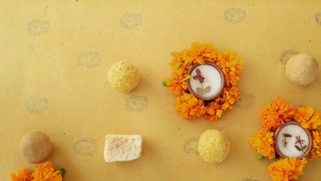 Human hand takes and then puts the last sweets along with flowers, diyas on a Indian background for Hindu festival of lights, Dusshera and Diwali preparation and celebration ingredients